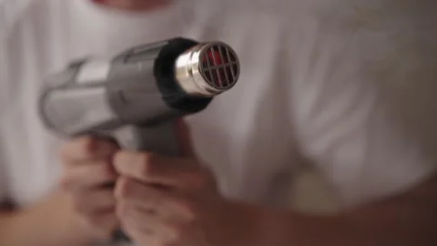 Close-up view of technician gripping hot air gun, glowing red heating element Stock Footage 317302736