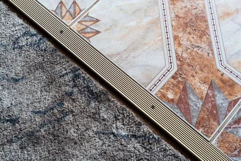 Close-up view of a textured carpet transitioning into an ornate patterned tile Stock Photos