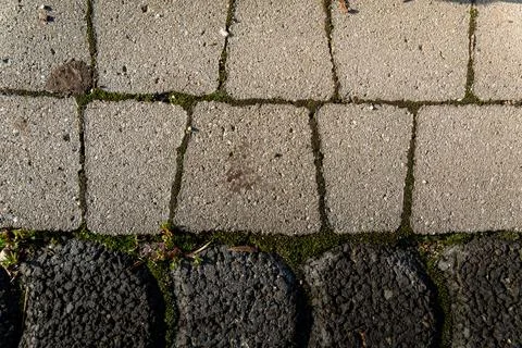 Close-up view of textured cobblestone and concrete pathway with moss growing in Stock Photos
