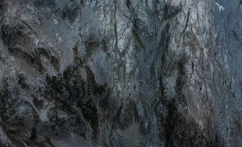 Close-up view of textured, dark gray rock face with crevices and varied tones Stock Photos