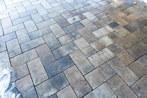 Close-up view of a textured, patterned pavement made of rectangular stone tiles. Stock Photos