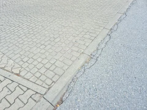Close-up view of textured pavement transition between cobblestone and asphalt Foto stock