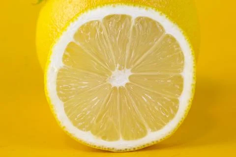 Close up view of textured ripe slice of lemon citrus fruit isolated on yellow Stock Photos