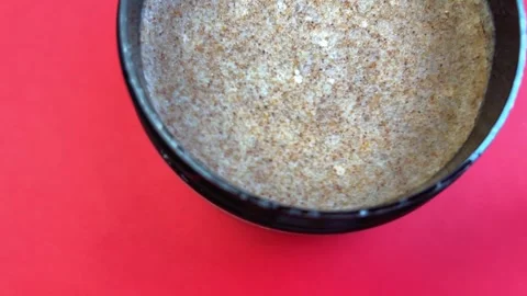 Close-up view of a textured scrub in a black container against a vibrant red Stock Footage 321739995