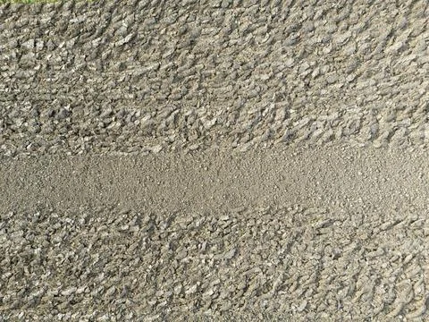 A close-up view of a textured surface showing tire tracks and gravel, perfect 스톡 사진