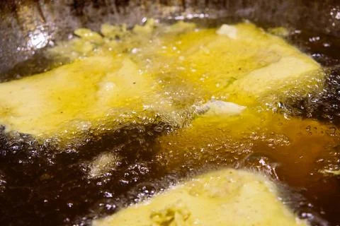 Close up view of thin battered tempeh mendoan sizzling in bubbling hot vege.. Stock Photos