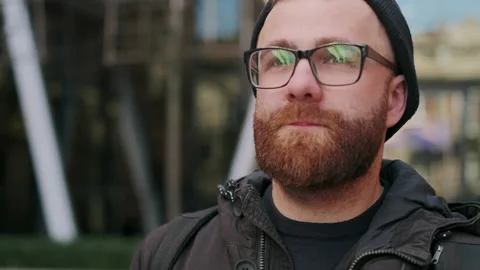 Close up view of thoughtful guy in glasses walking at city street. Portrait of Stock Footage 140195555