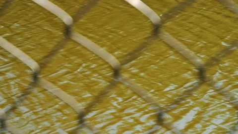 Close view through chain link fence to brown coastal water moving left to right. Stock Footage 293416391