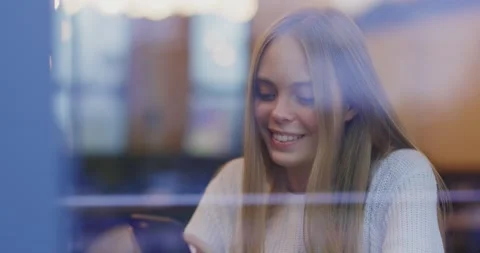 Close up view through the window of happy young woman use phone at cafe. Smiling Stock Footage 143736827