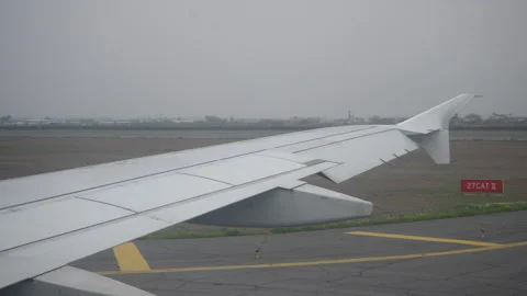 Close-up view through window on wing of airplane taxiing down runway, preparing Stock Footage 244386800
