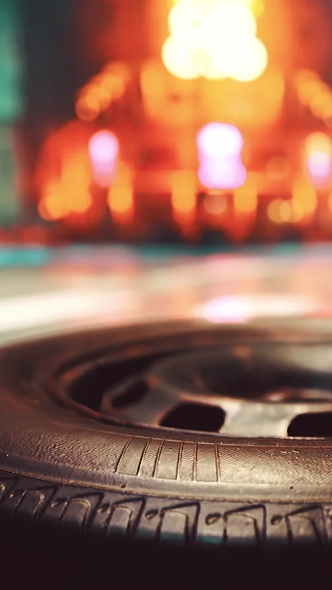 Close view of a tire with blurred city lights in the background at night Stock Footage 335690933