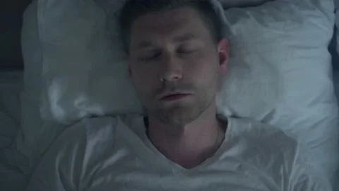 Close-up view of tired man falls on the bed in the evening and goes to sleep Stock Footage 218437830