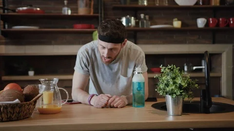 Close up view of tired young runner leaning over the kitchen table to catch his Stock Footage 111788687