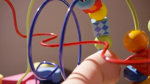 Close view of toddler's hand pushing several beads along a rollercoaster toy Stock-Footage 94636038