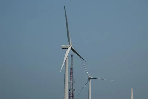 Close up view of the top of two wind turbines against a clear blue sky Stock Photos