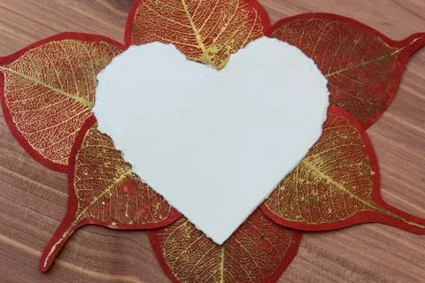 Close view of torn white paper heart with gold and red paper leaves Stock Photos