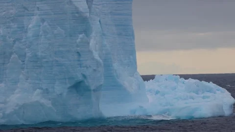Close view of a towering Antarctic iceberg drifting in dark ocean water Видео 335372230