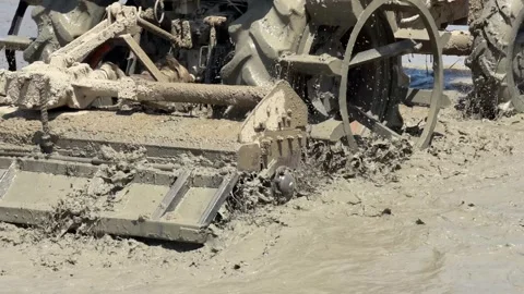 Close view of tractor blades stirring mud and water while shaping the paddy 库存影片 334091131