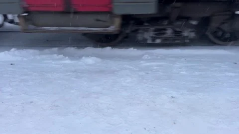 Close-up view of train wheels rolling through snow in winter, kicking up powd Stock Footage 325649398