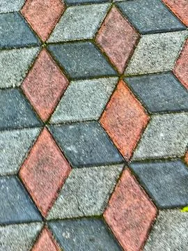 A close up view of triangular diamond shaped pavers in red and gray tones wit Stock Photos
