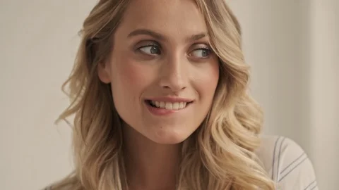 Close up view of tricky woman is biting her lip while looking around in studio Stock Footage 124961478