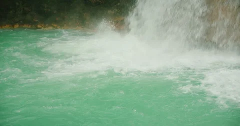 Close view of turquoise water swirling beneath a powerful rainforest waterfall Stock Footage 344773042