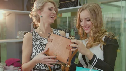 Close up view of two beautiful young blond women looking at a handbag's design Stock Footage 73962605