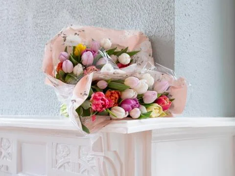 Close up view at two bouquets of blooming tulips, they lie on a white mantelp Stock Photos