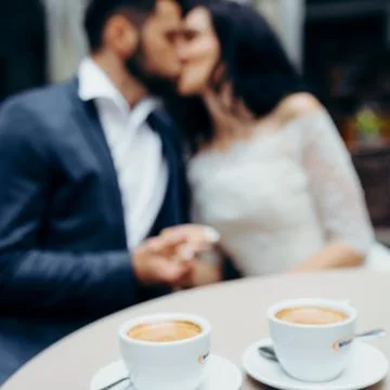Close-up view of the two cups of coffee at the blurred background of the kissing Stock Photos