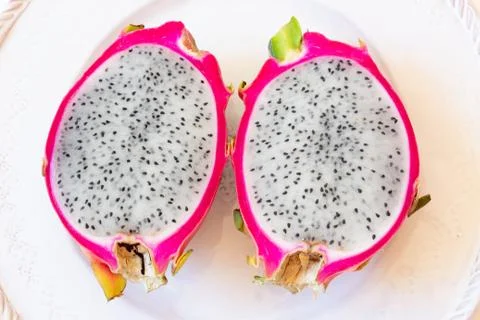 Close view of two cut white dragon fruit showing pink rind and black seeds Stock Photos