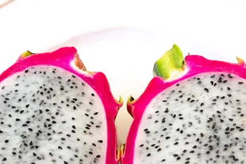 Close view of two cut white dragon fruit showing pink rind and black seeds Stock Photos