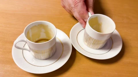 A close-up view of two empty coffee cups on saucers on a wooden table, one .. Stock Footage 333313668
