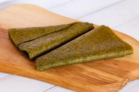 Close view of two folded green fruit pastille triangles on wooden cutting b.. Stock Photos