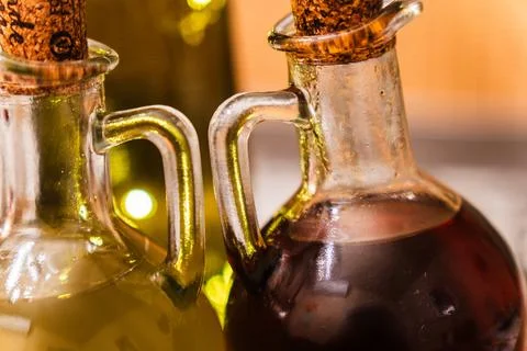 Close-up view of two glass bottles filled with oil on a wooden table in a cozy Stock Photos