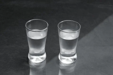 Close-up view of two glasses of vodka on black marble table Stock Photos