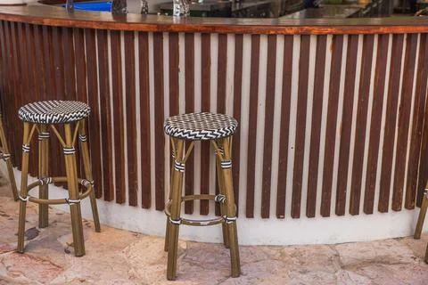 Close up view of two high bar stools with woven seats standing by wooden counter Stock Photos