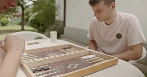 Close-up view of two people playing a backgammon board game outdoors. Hands Stock Footage 282560135