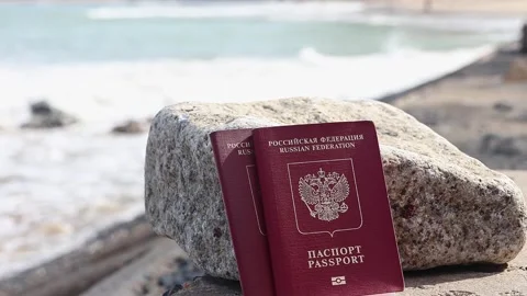Close up view of two russian passports with ocean waves in background. Stock Footage 289406949