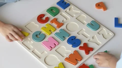 Close-up view, two young boys actively assemble a bright alphabet puzzle on a Stock Footage 318294581
