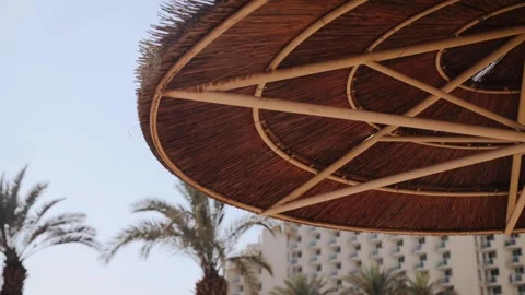 Close up view from under a straw umbrella to the clear blue sky, on a sandy Stock Footage 183395443