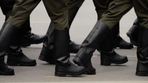 Close-up view of uniformed boots marching in synchronized formation along a city Stock Footage 317561977
