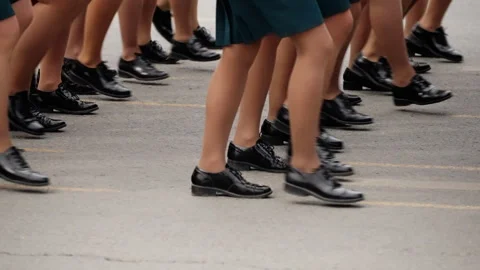 A close-up view of a uniformed group marching in precise formation along a city Stock Footage 317562036