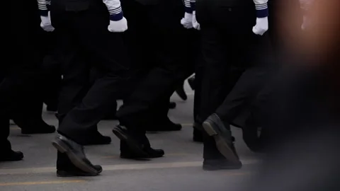 Close-up view of uniformed marchers stepping in unison along a street, polished Video stock 317565848