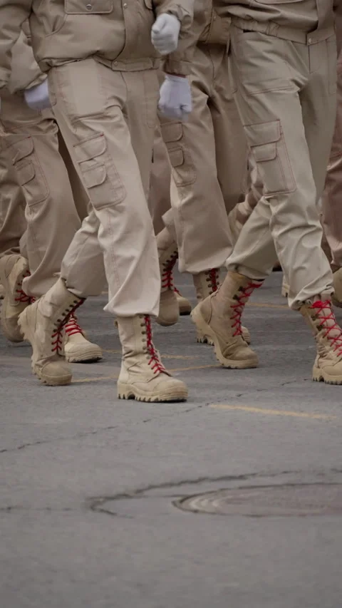 Close-up view of uniformed troops in tan utility uniforms marching in precise Stock Footage 317560320