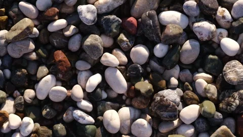 Close-up view of various smooth pebbles and stones on a beach, showcasing a 動画素材 346724097