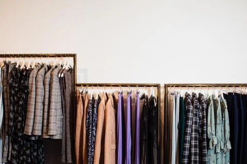 Close-up view of various stylish clothes hanging on hangers in boutique. Clothes Stock Photos