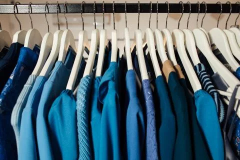 Close-up view of various stylish clothes hanging on hangers in boutique. Clothes Stock Photos