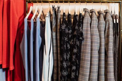 Close-up view of various stylish clothes hanging on hangers in boutique. Clothes Stock Photos