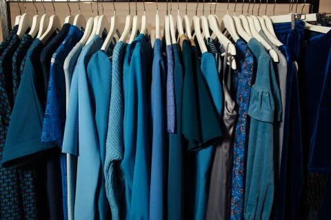 Close-up view of various stylish clothes hanging on hangers in boutique. Clothes Stock Photos