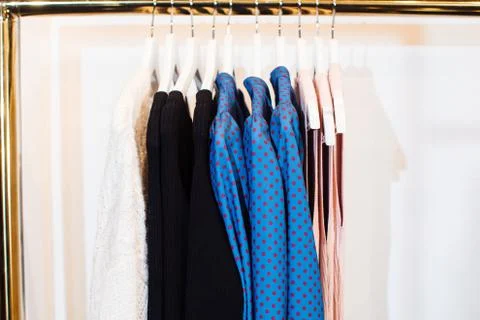Close-up view of various stylish clothes hanging on hangers in boutique. Clothes Stock Photos